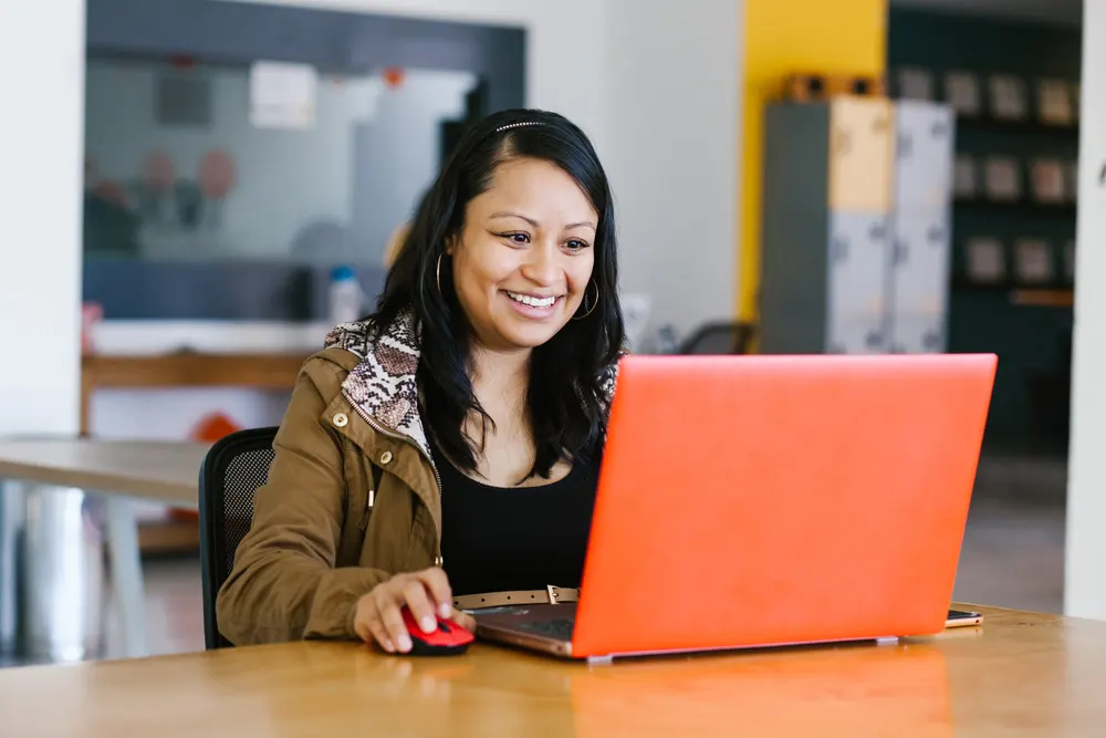 Profesionista sonriente atendiendo una videollamada desde su escritorio