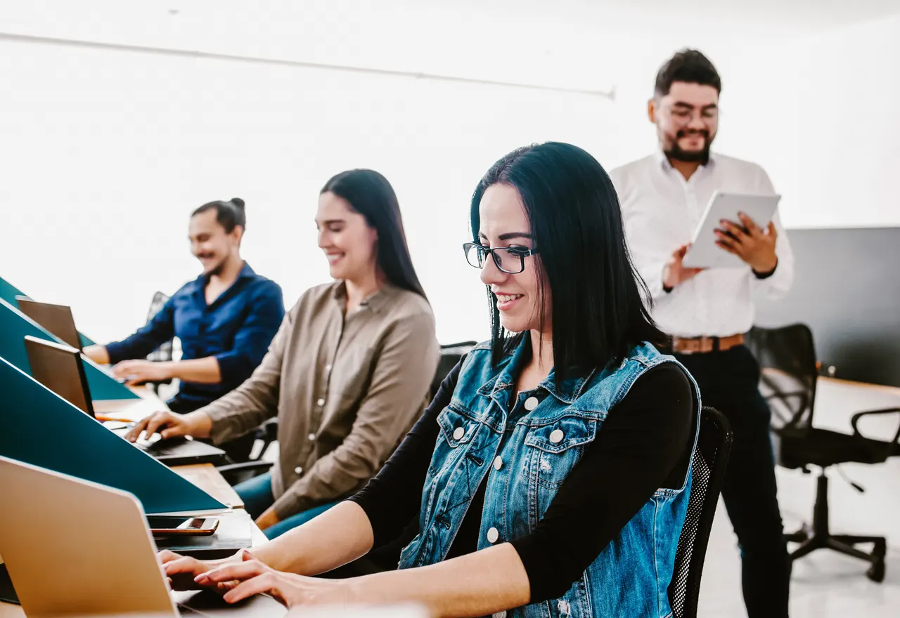 Facilitador trabajando con un grupo reducido de profesionistas frente a sus computadoras