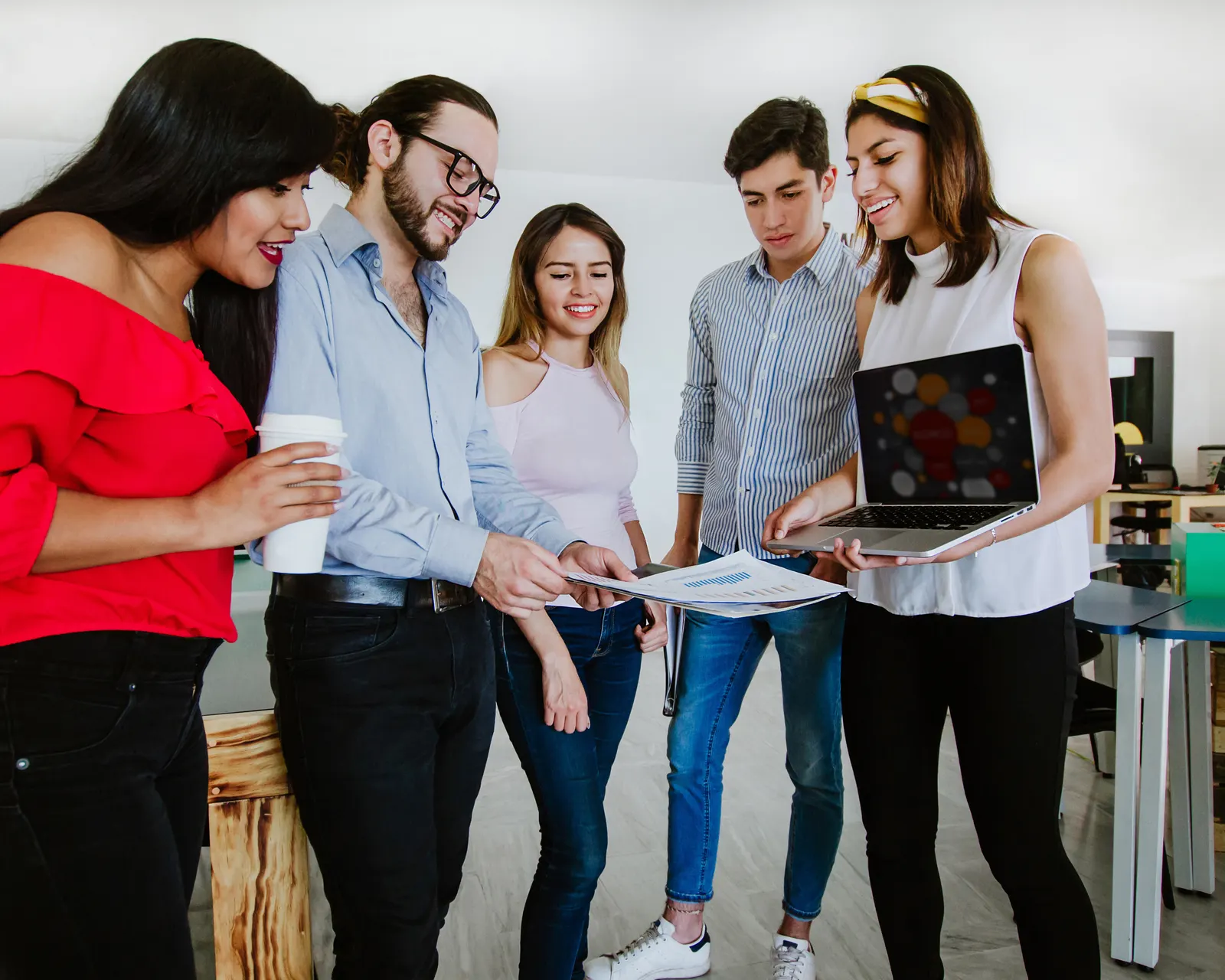 Grupo de profesionistas jóvenes revisando juntos un proyecto en una oficina luminosa