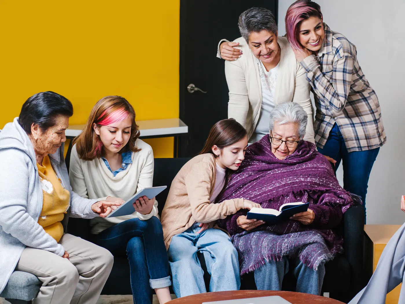 Familia mexicana de varias generaciones leyendo un libro junto a la abuela