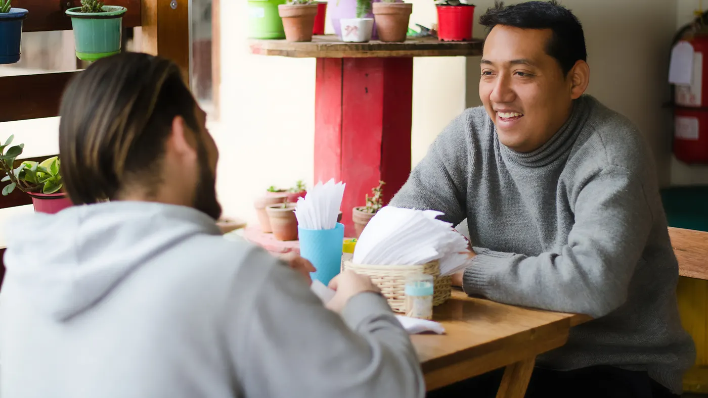 Dos colegas conversando animadamente en la mesa de un café